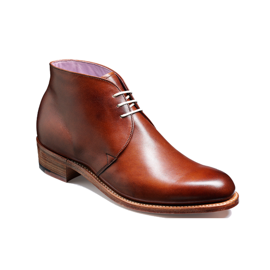 A brown leather ankle boot with a low stacked heel, silver-toned laces, and a light purple lining, shown from a three-quarters angle on a white background.